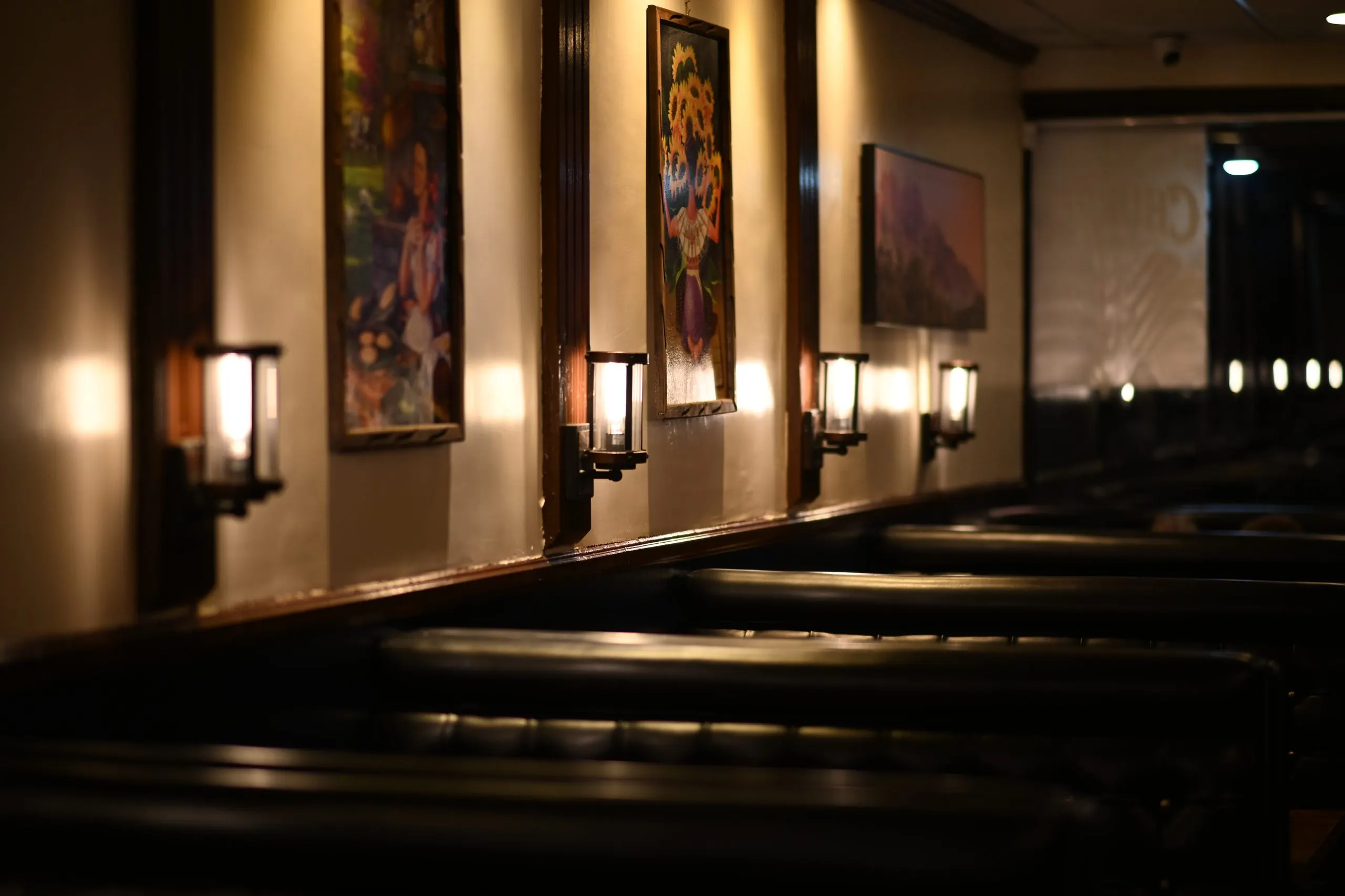 The Playa Azul dining room at night — wall sconces, framed art and tufted leather booths